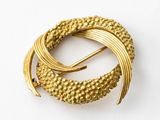 an image of a gold broochle with a spiral design