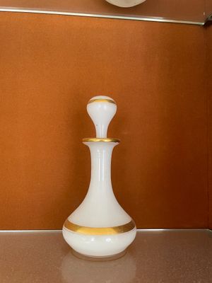un vase blanc posé sur un comptoir, avec une horloge accrochée au mur derrière lui