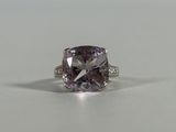 a close up of a ring with a purple diamond on a table