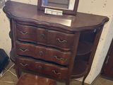 a dresser with a mirror and a stool in a room