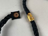 a close up of a black cord with a gold clasp