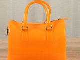 an orange handbag sitting on top of a table next to a curtain