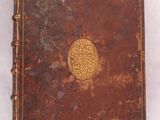 un vieux livre marron orné d'un médaillon doré sur la couverture