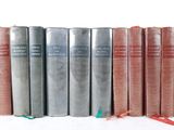 several old books are lined up in a row on a white surface