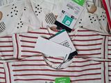 a pile of baby clothes on a bed with tags on them