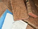 many old books on a table with papers on it