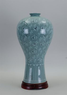 un vase bleu posé sur un socle en bois, sur fond blanc