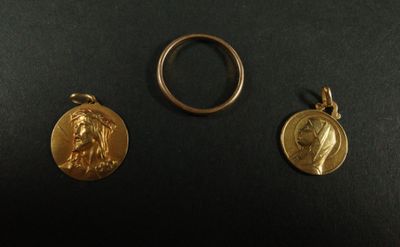 deux médailles d'or et une bague posées sur un fond noir