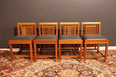 quatre chaises en bois posées sur un tapis devant un mur gris