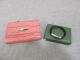 a pink purse and a green box on a bed