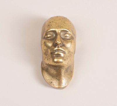 brass statue of a man ' s head on a white surface