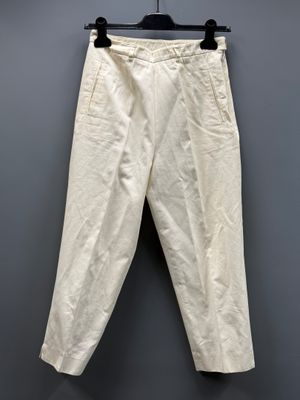 un pantalon blanc suspendu à un cintre devant un mur gris