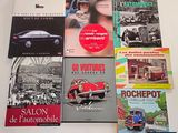 several books on a table with a red car in the background
