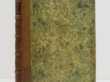 an old book sitting on top of a white table next to a white wall