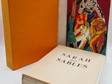 an orange book sitting next to a stack of books on a white surface