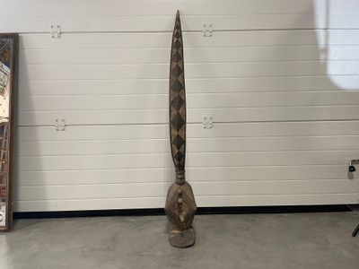 une sculpture en bois représentant un homme tenant une planche de surf devant un mur
