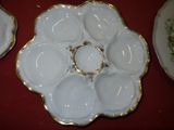 two white plates with gold rims on a red table