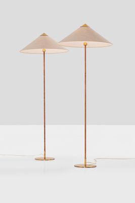 a pair of brass floor lamps on a white surface