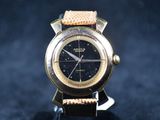 une montre en or avec un cadran noir posée sur un fond noir