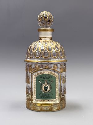 une bouteille en verre doré et vert, surmontée d'une horloge
