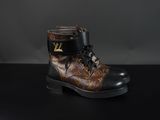 Des bottes Louis Vuitton posées sur une surface noire, sur fond gris