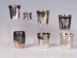 several silver cups and cups with designs on them on a table
