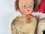 two dolls sitting next to each other on a white surface