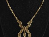 a gold necklace on a black mannequin with a gold chain