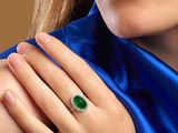 close up of a woman wearing a ring with a green stone on it