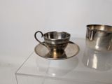 a silver cup and saucer sitting on a glass table