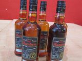 quatre bouteilles de whisky sont posées sur une table devant un mur rouge