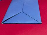 a close up of a folded blue envelope on a red surface