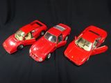 three red toy cars sitting next to each other on a black surface