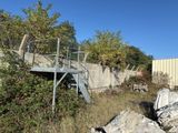 a metal stair going up to a building next to a pile of rocks