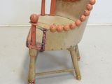 a small chair made out of wood with beads on it