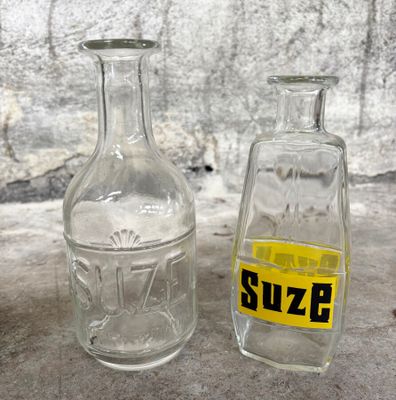 deux bouteilles en verre posées l'une à côté de l'autre sur une table