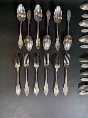 un grand nombre de cuillères et de fourchettes disposées sur la table
