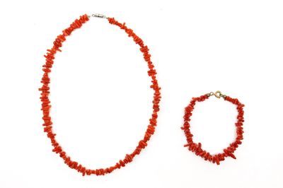 collier et bracelet composés de perles de corail rouge sur fond blanc