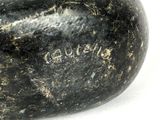 a black rock with writing on it sitting on a white surface