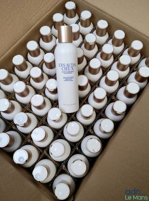 a cardboard box with a lot of cups and a bottle of lotion in it