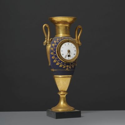 un vase ancien bleu et or, surmonté d'une horloge