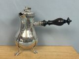 a silver coffee pot sitting on top of a wooden table