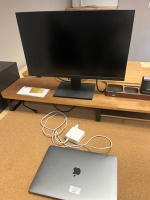 un bureau sur lequel se trouvent un ordinateur portable, un écran et d'autres appareils électroniques