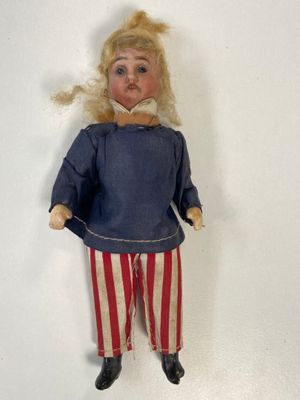 an old fashioned doll with blonde hair and red and white striped pants