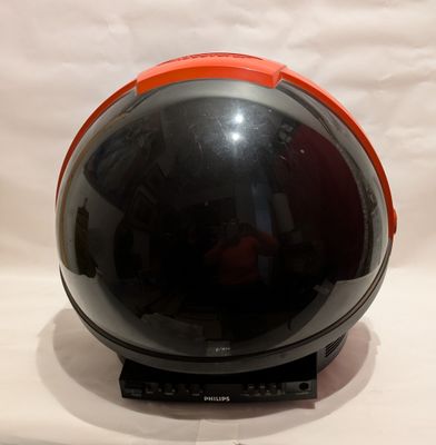 un casque noir et orange posé sur un support, sur fond blanc