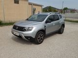 La Dacia argentée est garée sur un parking près d'un immeuble.