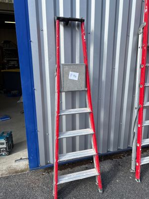 deux échelles rouges appuyées contre un mur devant un immeuble