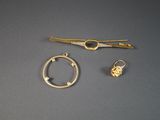 deux bijoux en or posés sur une surface grise