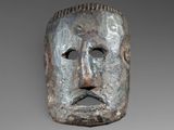 a close up of a metal mask on a gray background