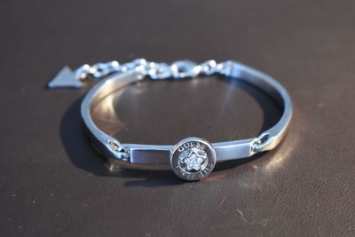 silver bracelet with a diamond on it sitting on a table